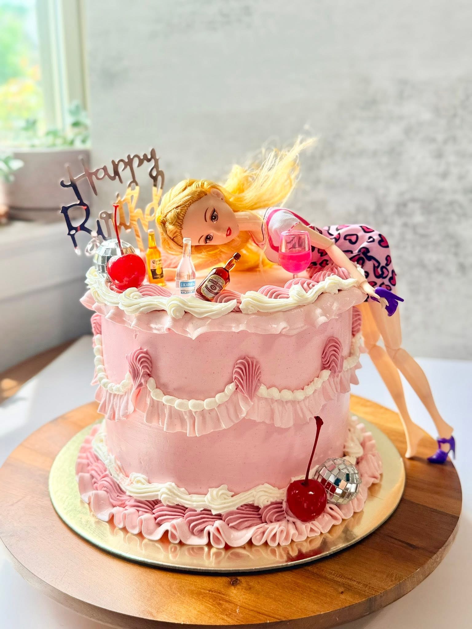 Pink vintage ruffle cake with a party doll topper